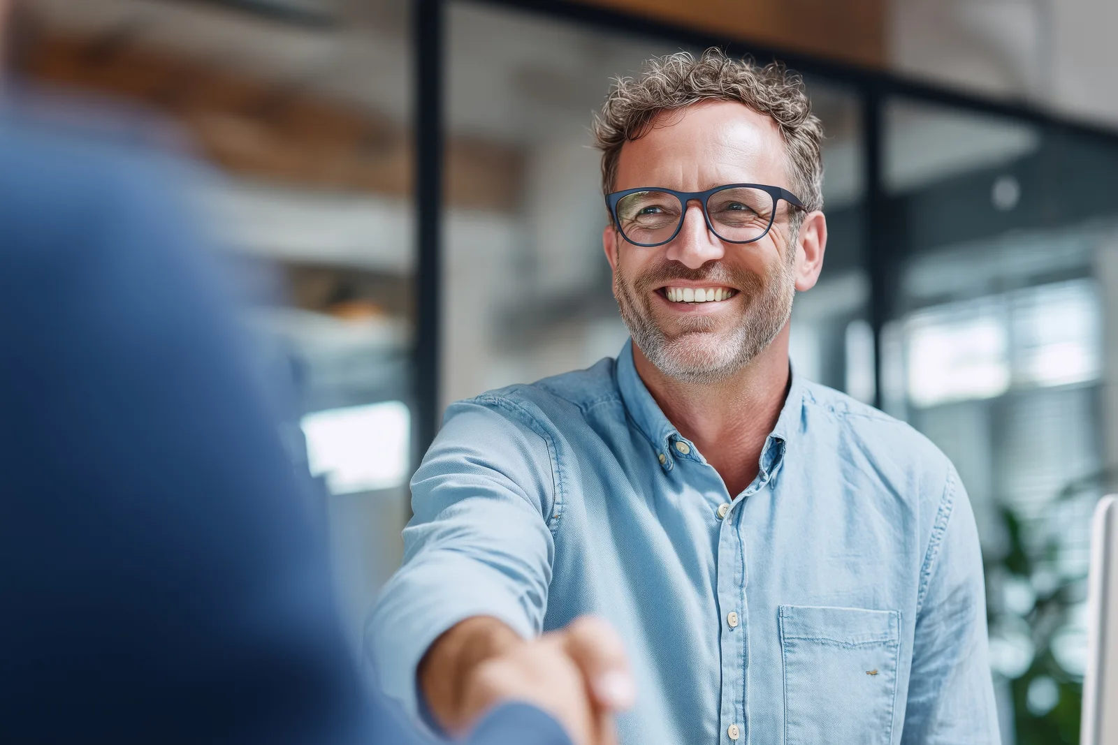 A smiling business owner shaking hands with a customer, representing relationships built in person and strengthened online.